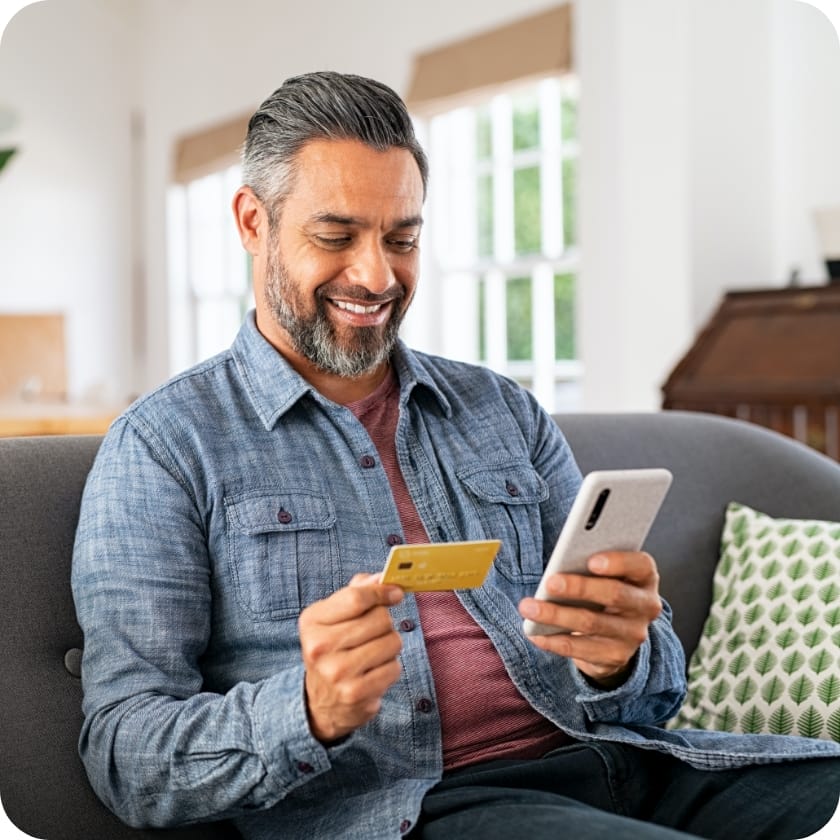 Man looking at a credit card and his phone